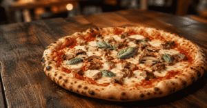 Best pizza in London with sausage, mushrooms, mozzarella and basil on a rustic wooden table.