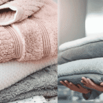 Stack of fluffy white bath towels neatly folded on a wooden bathroom shelf