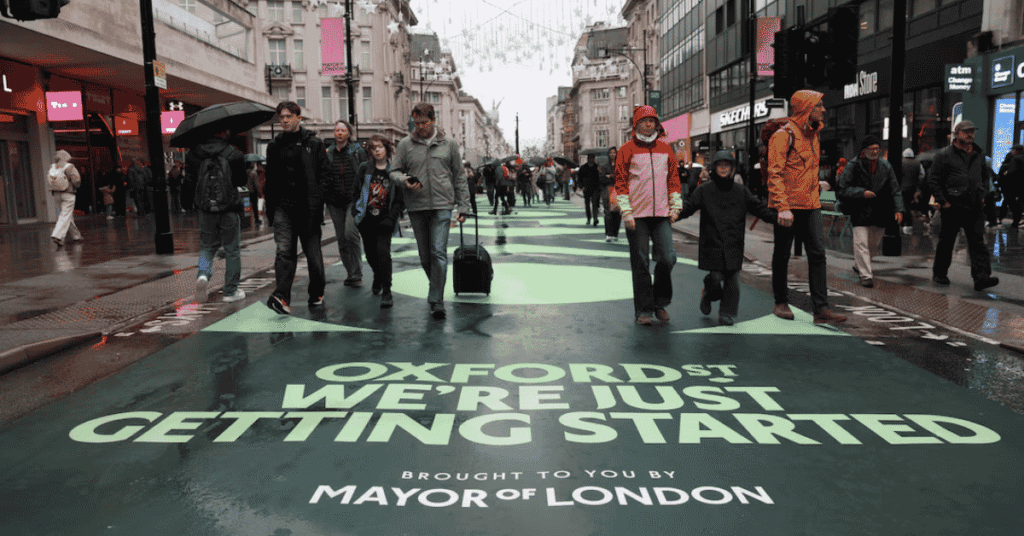 Crowds walking along a traffic-free Oxford Street in central London with historic department stores in view