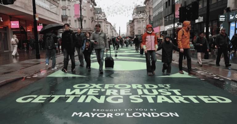 Crowds walking along a traffic-free Oxford Street in central London with historic department stores in view
